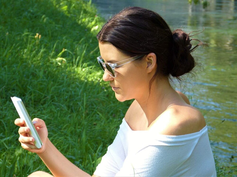 Frau am See mit Handy